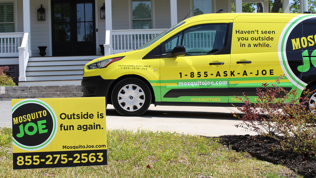 Mosquito Joe van parked in front of house with a Mosquito Joe lawn sign.