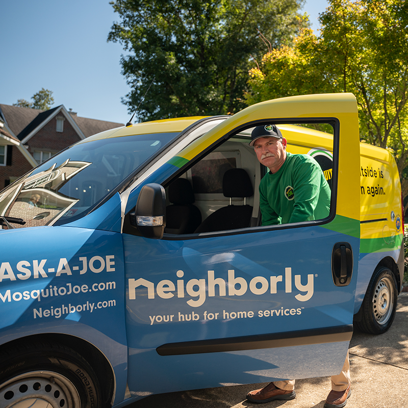 Mosquito Joe professional standing outside company van with the door open.