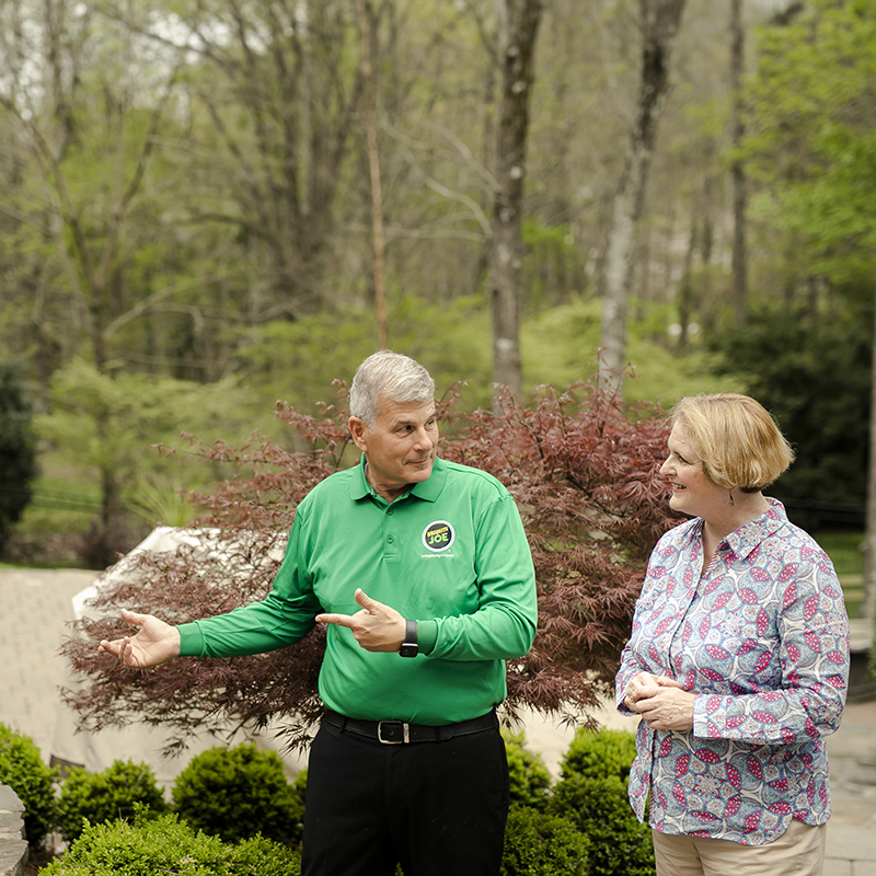 Mosquito Joe professional talking with female customer while outside in the yard.