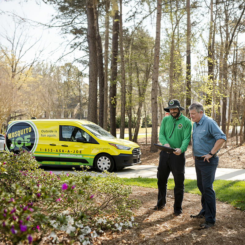 Mosquito Joe professional talking with male customer while outside in the yard.