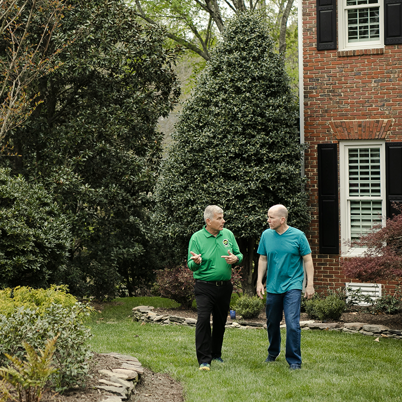 Mosquito Joe professional talking with male customer while walking outside in the yard.