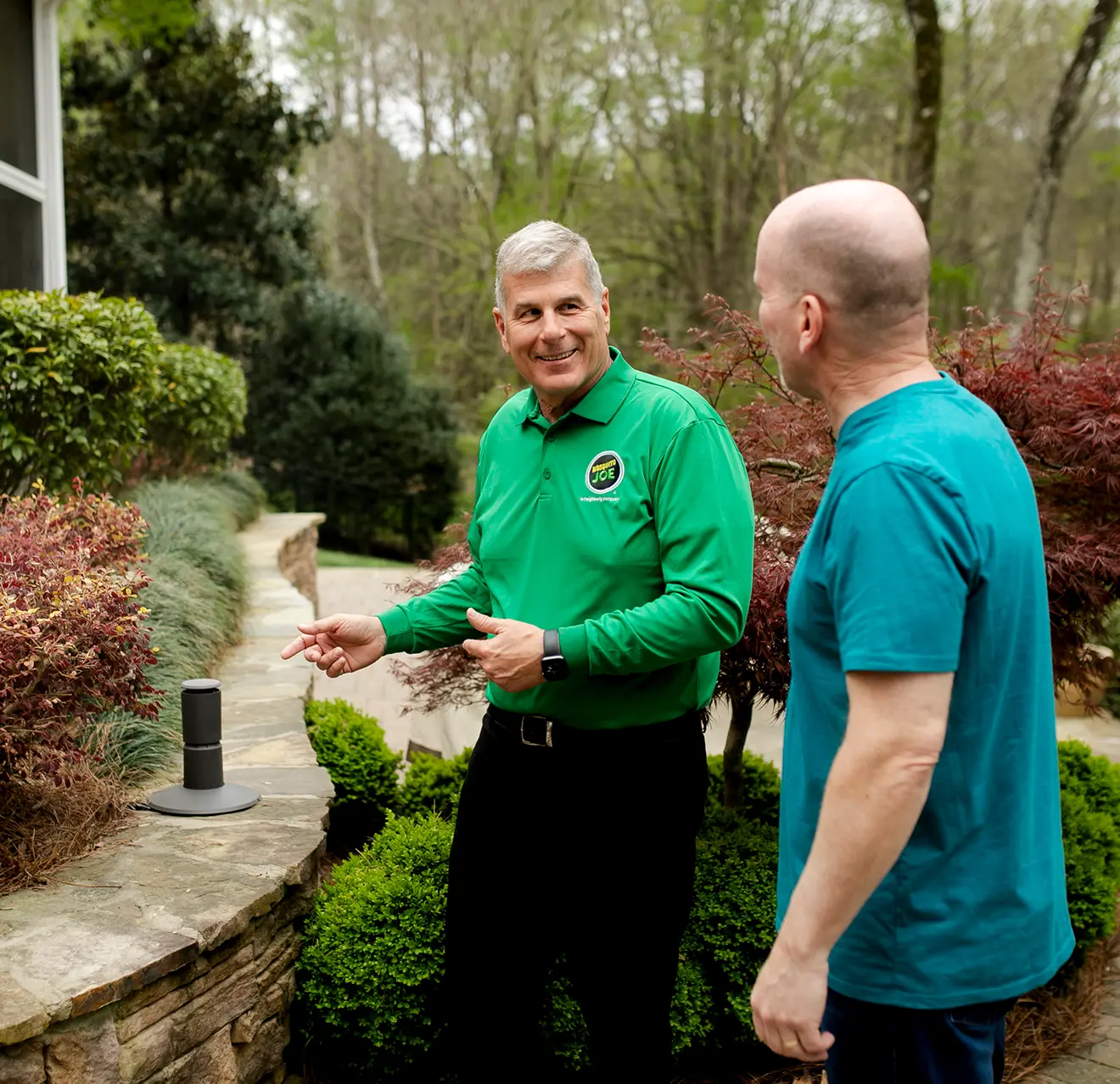 A Mosquito joe technician talking to a customer outside their home.