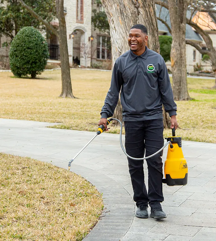 Smiling Mosquito Joe professional carrying a sprayer.