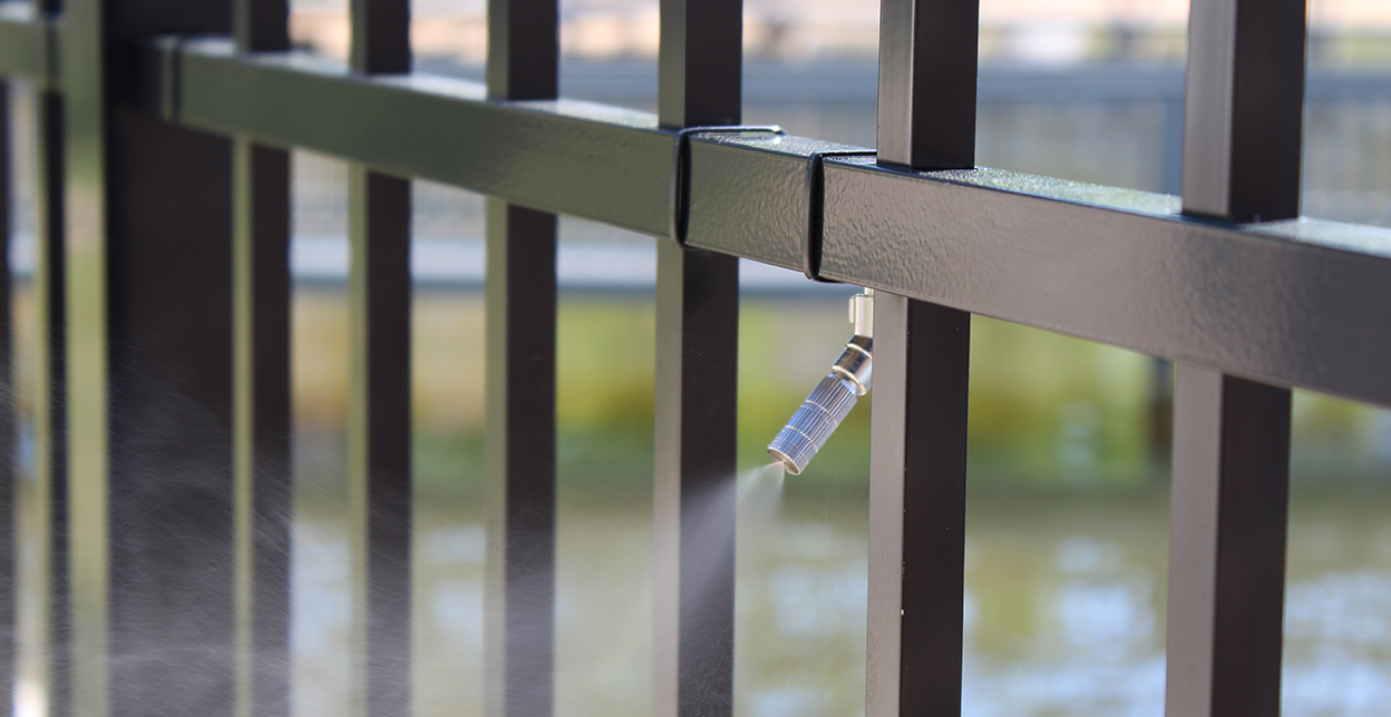 Barrier spray system on black metal gate.