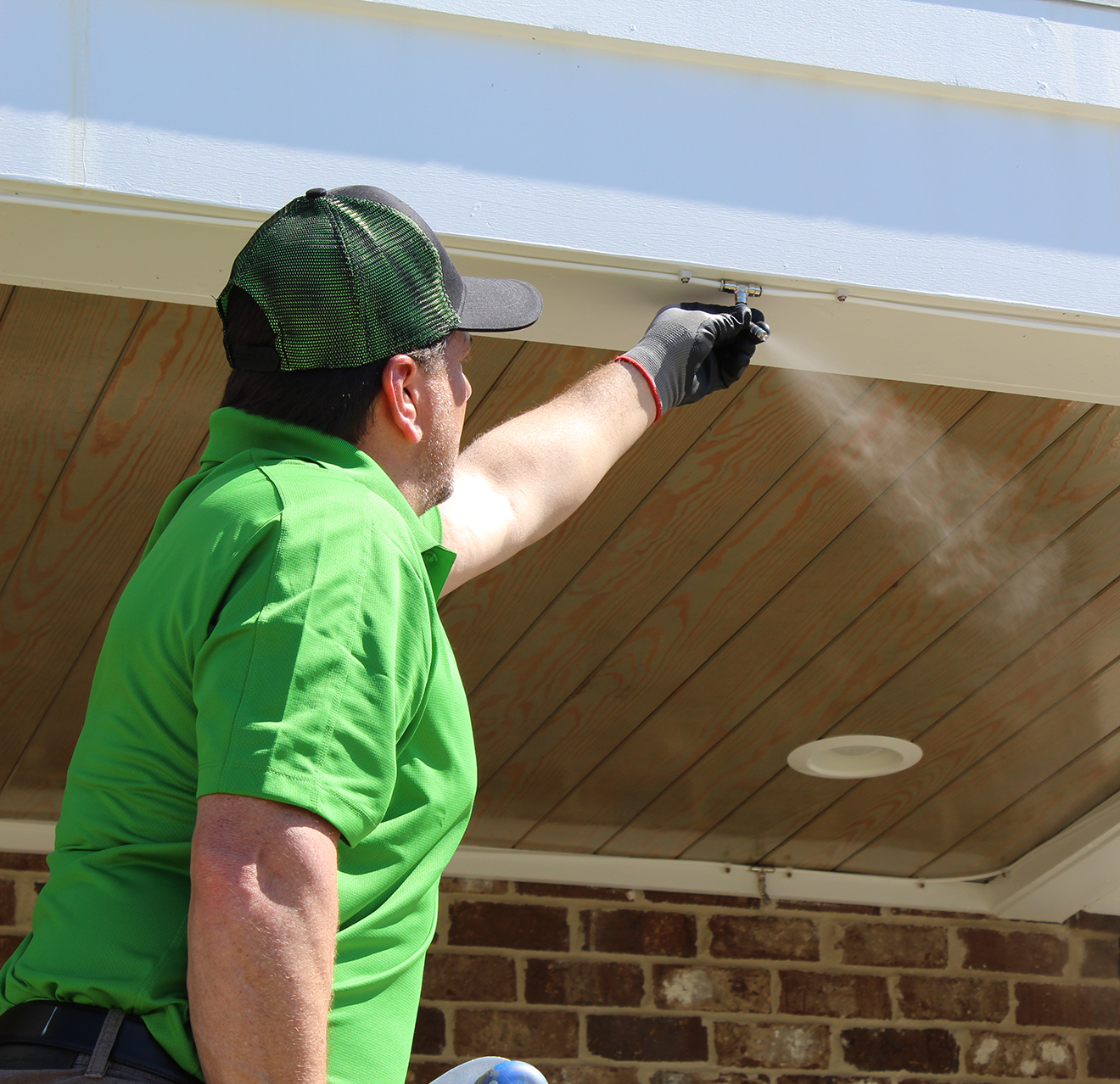 Mosquito Joe professional adjusting spray nozzle on roof.