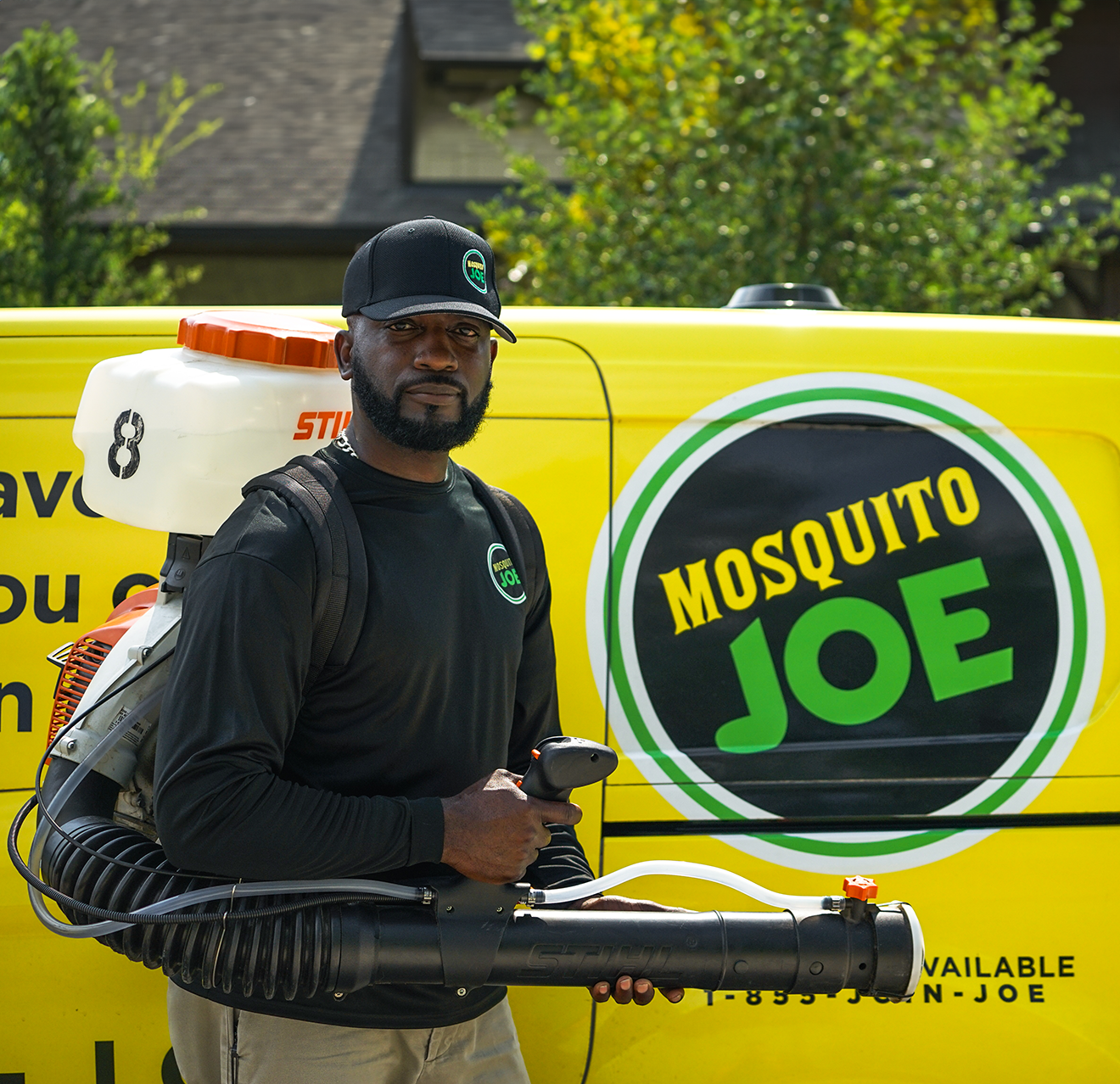 A Mosquito Joe employee with a chemical sprayer in front of a Mosquito Joe van.