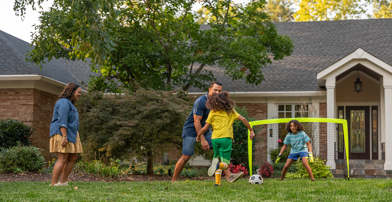 Family playing soccer in the yard.