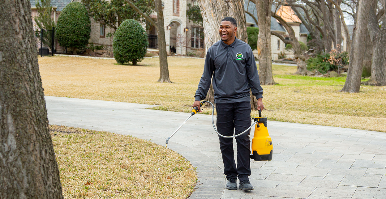 Smiling Mosquito Joe professional carrying a sprayer.