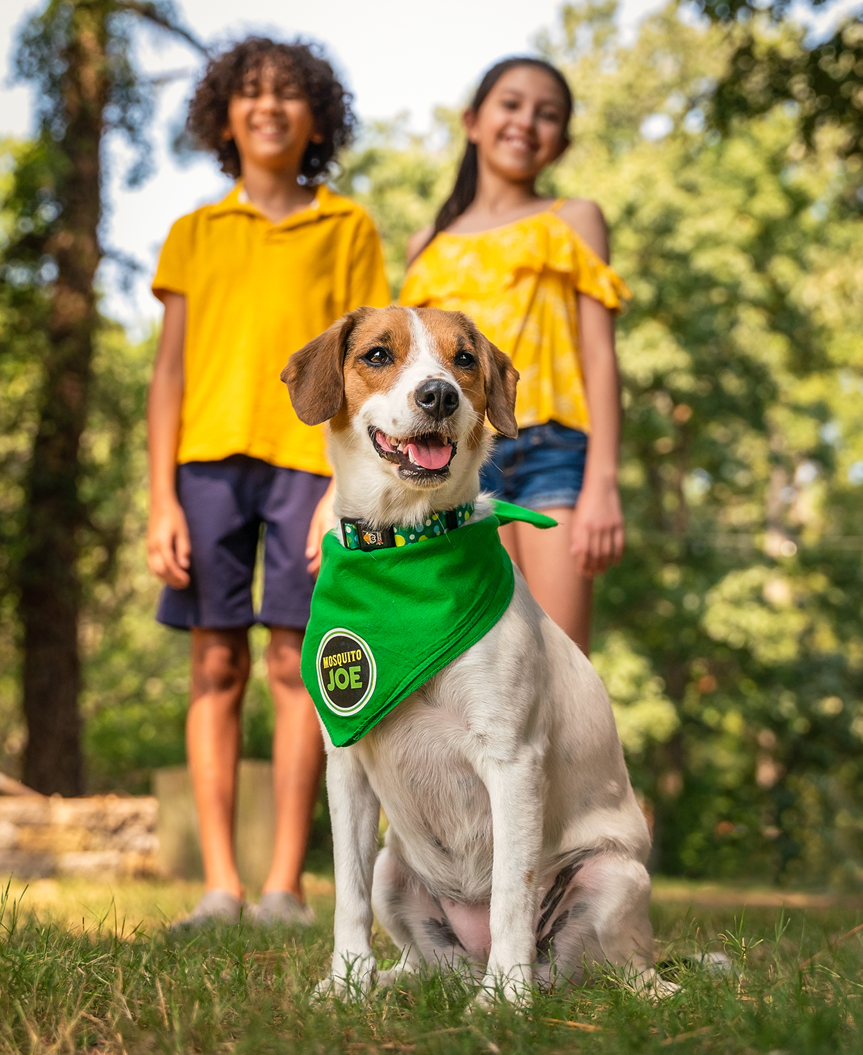 Two kids posing with a dog in a Mosquito Joe bandana around it's neck.