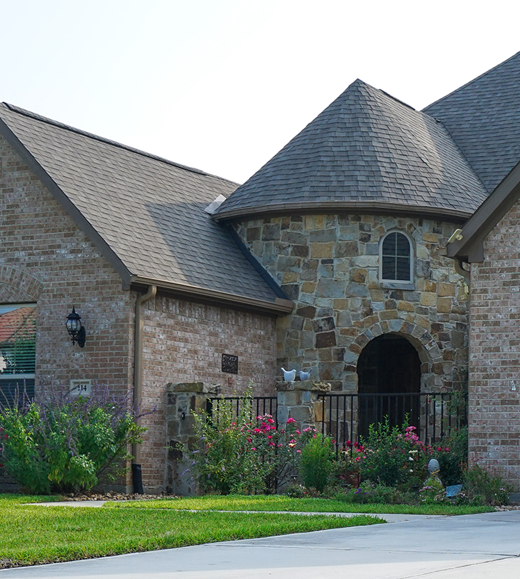 View of stone house with a landscaped front yard.