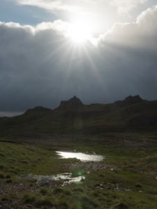 A bright sun shines over a mountain range.