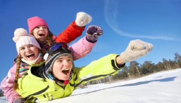 Teens sliding down snow-covered hill in winter.