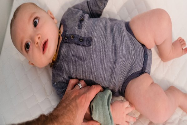 Baby in a crib with the parent putting ointment on a mosquito bite.