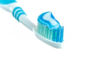 Blue toothpaste on a toothrush that is both blue and green.