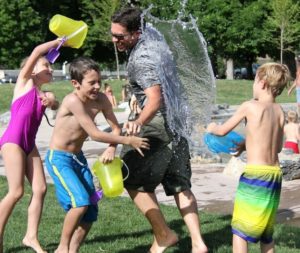 Family playing with water buckets outdoors.