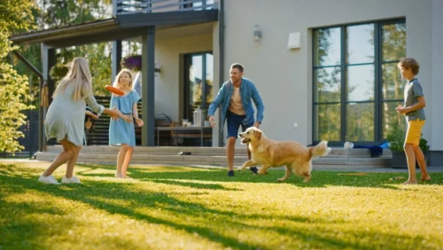 Happy family playing with a frisbee outside with golden retriever.