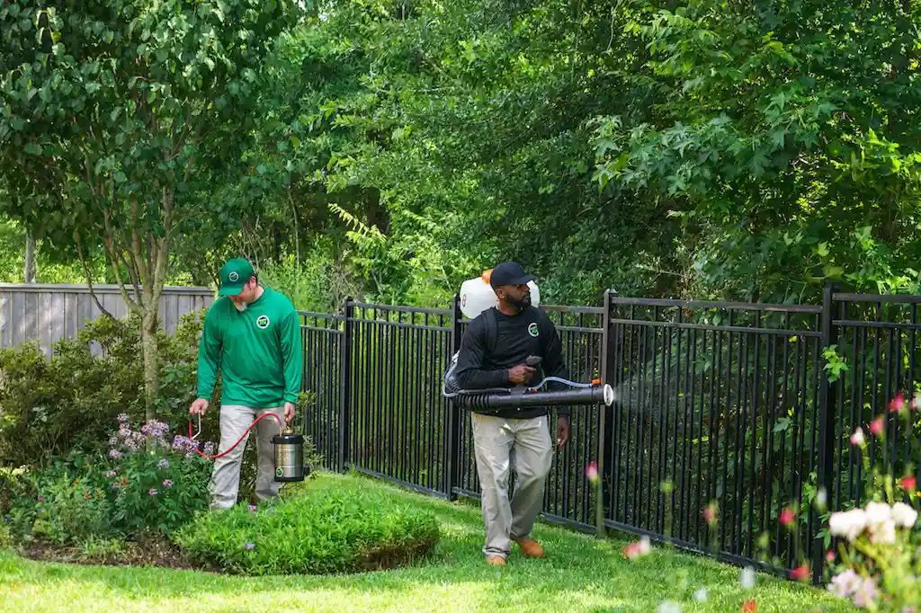 Mosquito Joe Technicians wearing green and black longsleeve applying barrier treatments.