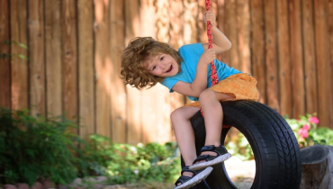 A young boy joyfully swings on a tire swing.