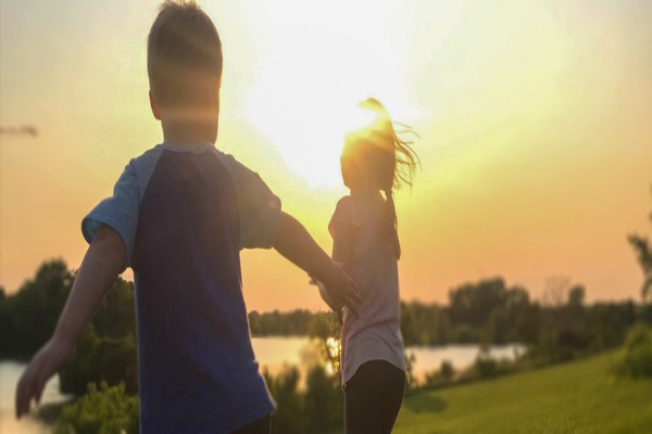 Kids running around outside as the sun sets.