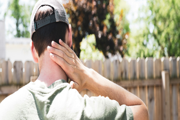 Back view of man scratching a mosquito bite on his neck.