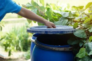 A man opening trash can lid outside.