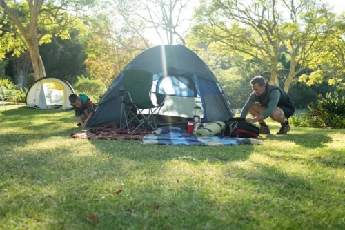 Father and son setting up tent at their campsite.