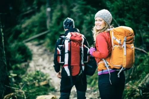 Man and woman hikers trekking through the woods.