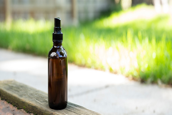 A bottle of homemade mosquito repellent placed in an outdoor setting.