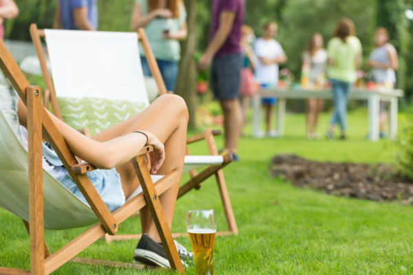 Outdoor picnic with close up of a woman in a folding chair with a beer on the ground.