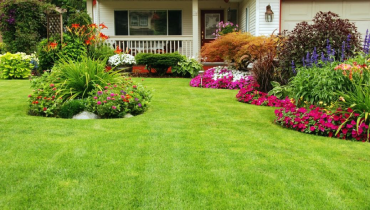 Exterior of a suburban home with a healthy green lawn and manicured flower beds in bloom.