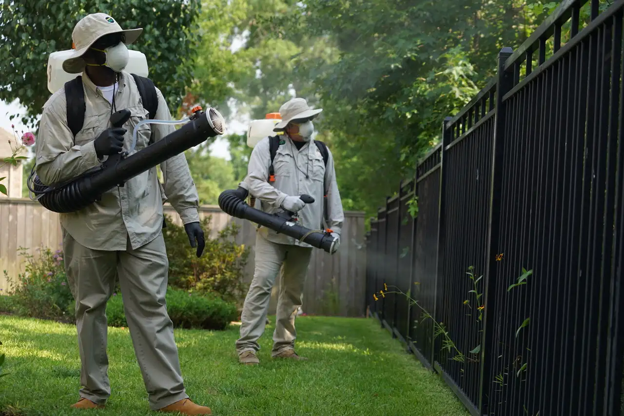 Mosquito Joe technicians in protective gear applying barrier treatments.