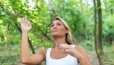 Young woman outside swatting at group of mosquitos buzzing around her face.