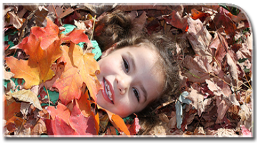 A small girl rests in fall leaves.