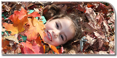 A small girl rests in fall leaves.