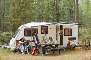 Group of friends enjoying the outdoors under tent and outside of rv.