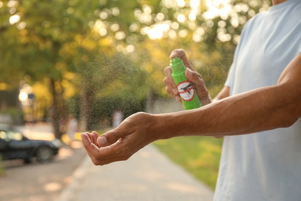 Person spraying mosquito spray on the arm