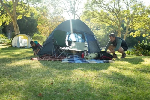 Father and son setting up tent at their campsite