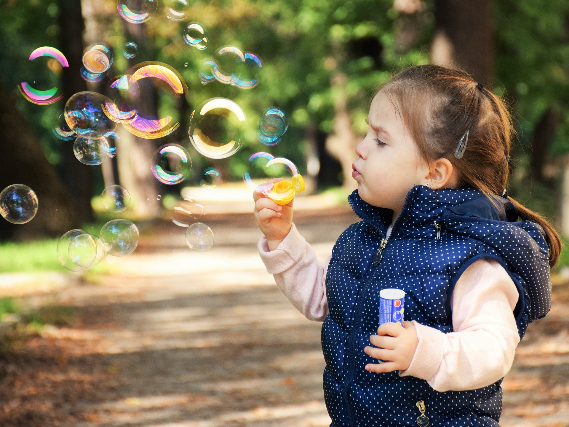 Little girl enjoying a day outdoor blowing bubbles