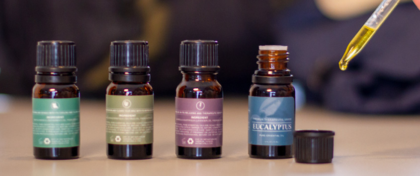 Four bottles of essential oils in a row with a dropper