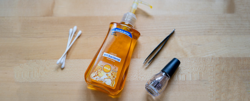 Bottle of antibacterial soap with tweezers, cotton swabs, and rubbing alcohol