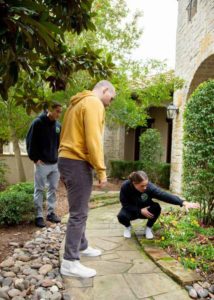 Two mosquito joe technicians show a homeowner how the perimeter pest treatment can be applied to their flowerbeds