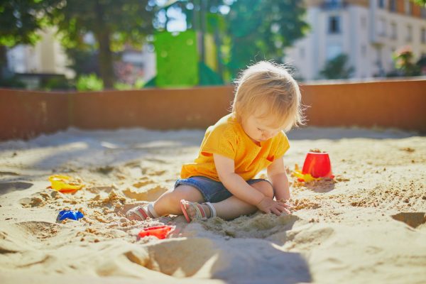 Toddler playing in a bug free sand box with his toys