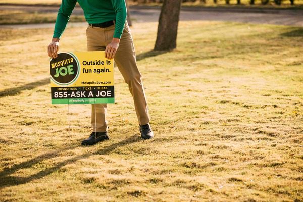 Mosquito Joe Service Professional placing yard sign in customer lawn. 